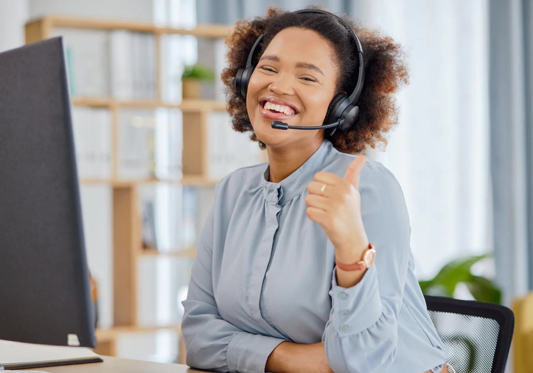 Happy woman help desk agent wearing a headset and giving a thumbs up